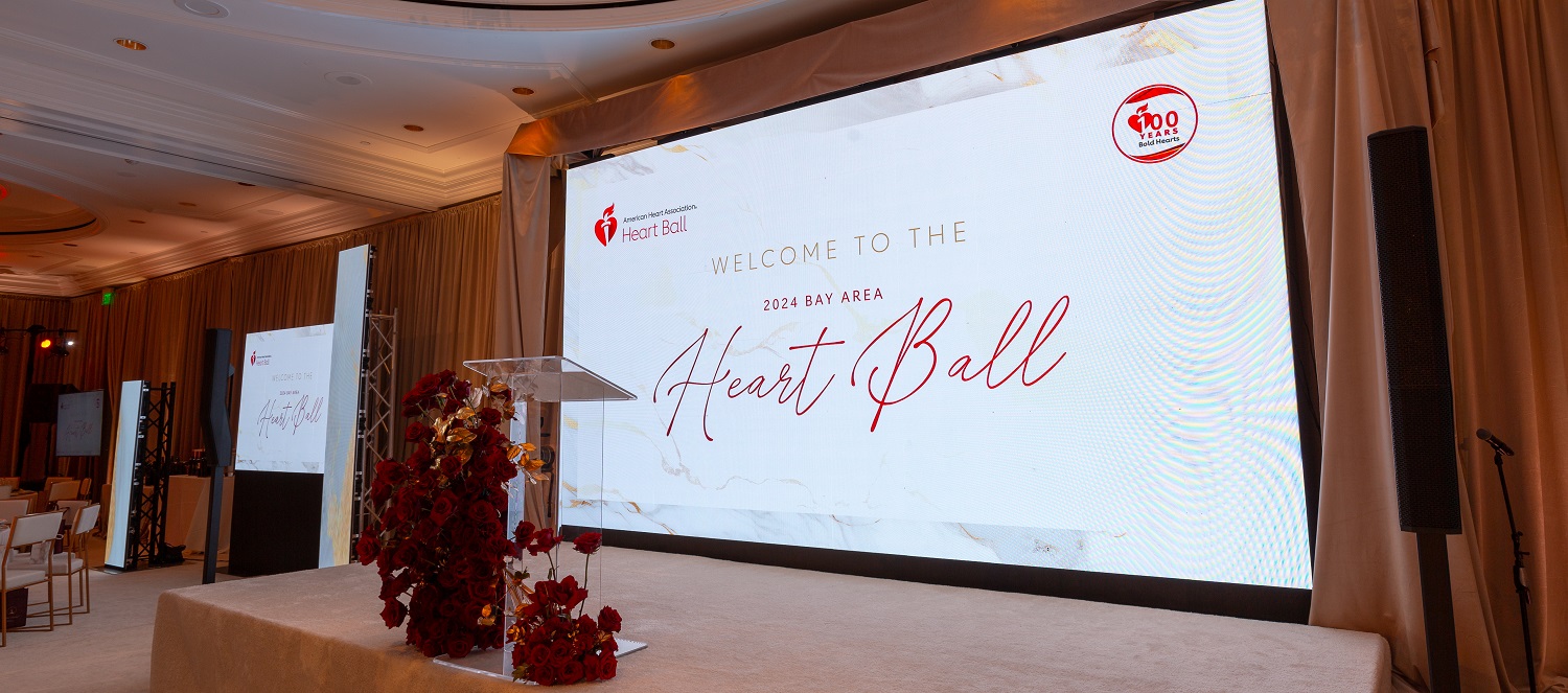 Photo of empty stage with large screen reading Welcome to the Heart Ball